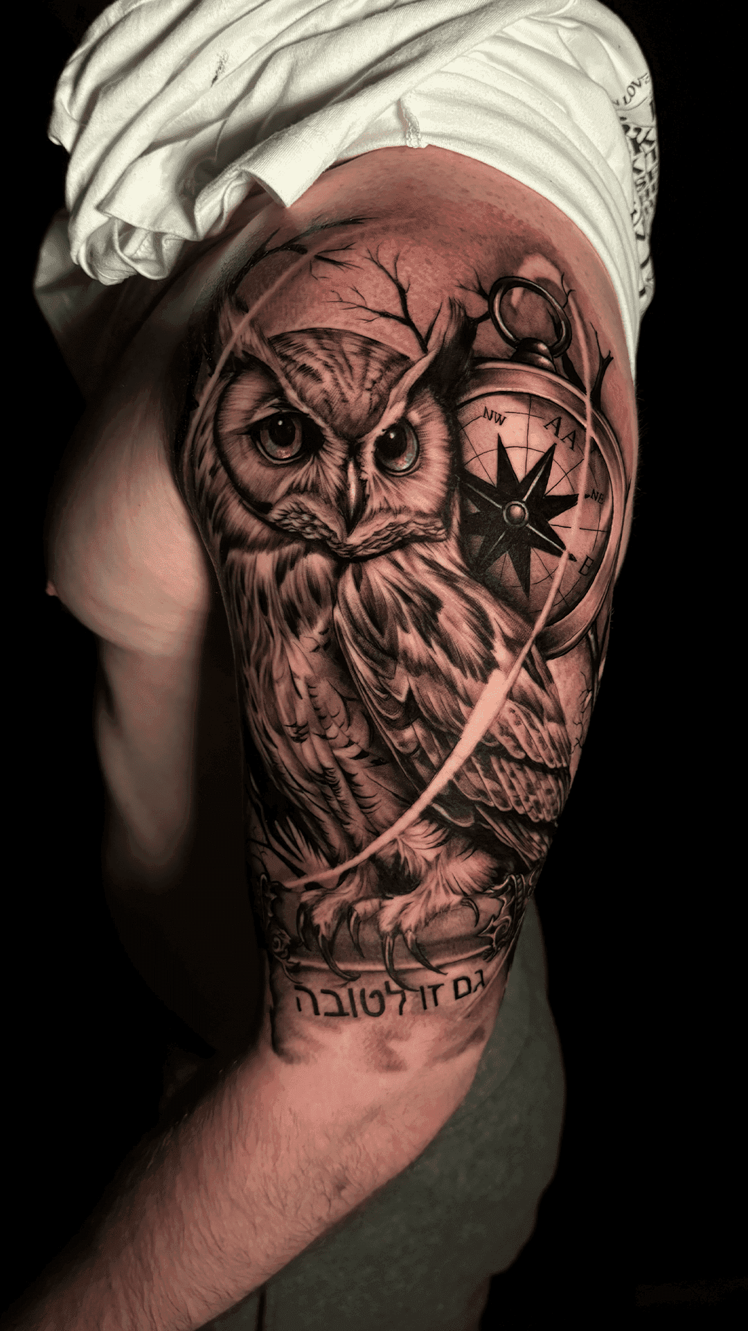 Black-and-grey realism owl with a compass on the upper arm