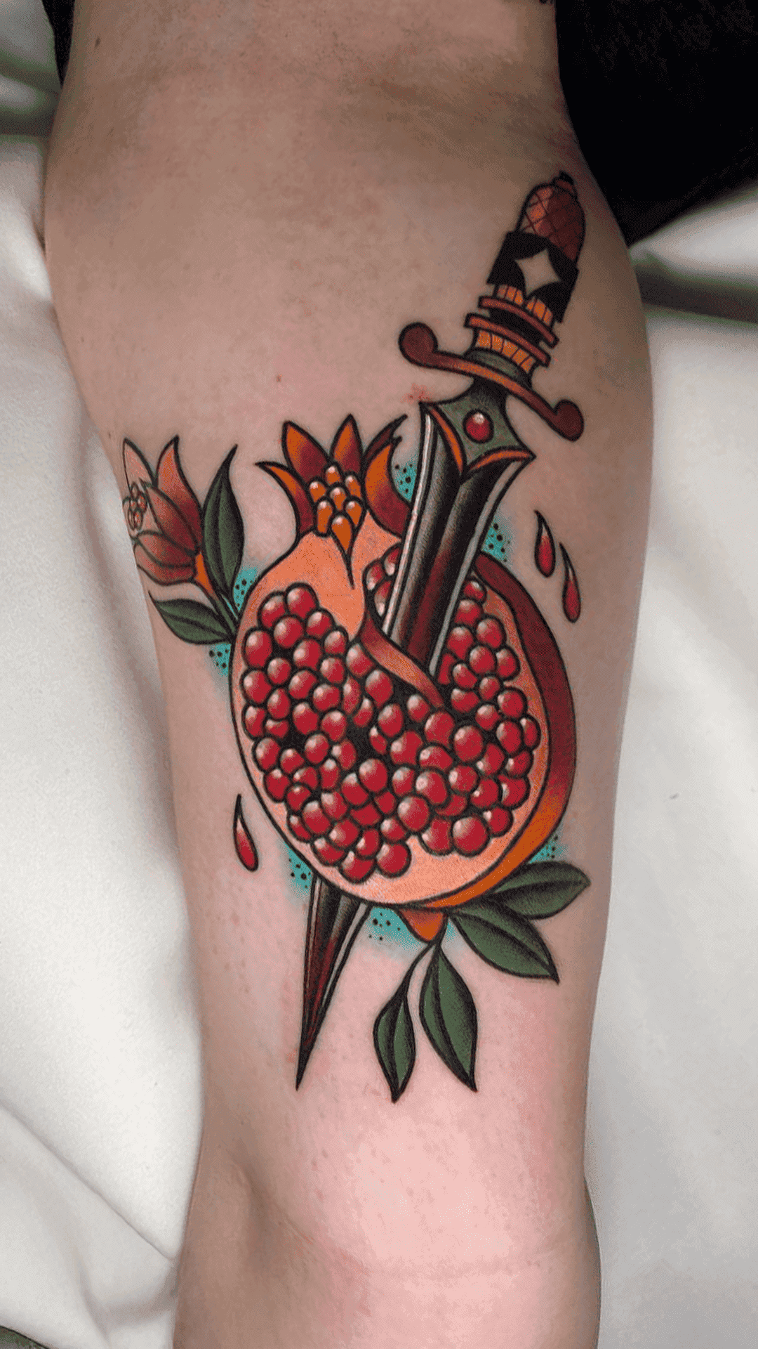 Traditional color tattoo of a dagger driven through a pomegranate