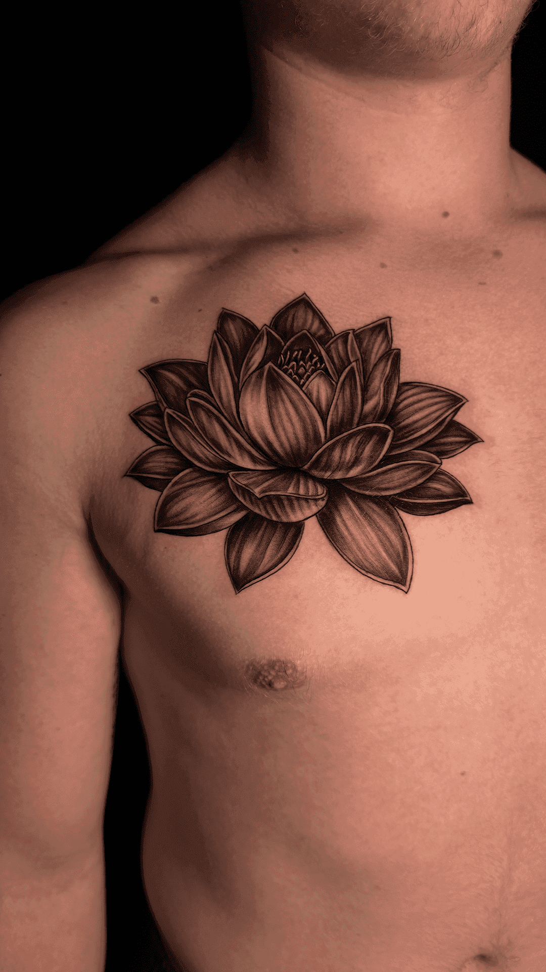 Black-and-grey lotus flower tattoo on the chest